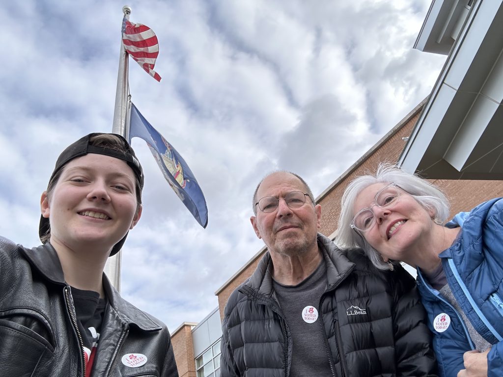 The Corrado-Green family wearing "I Voted Today" stickers, posing near a flag pole